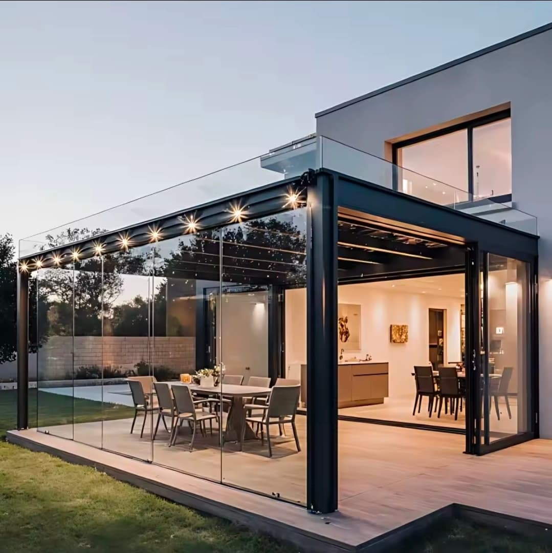 Glass aluminium pergola enclosure at night with string lights