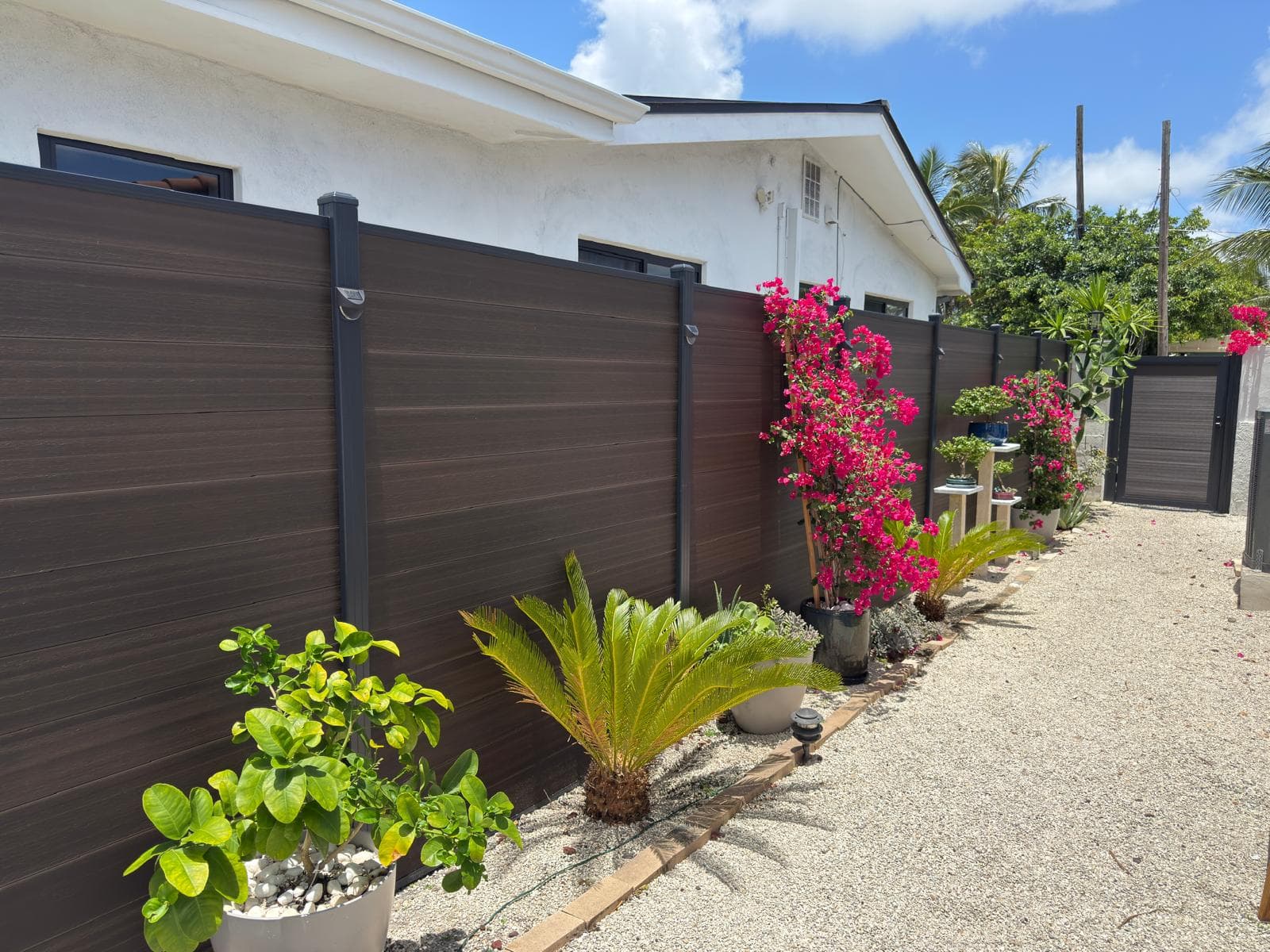 Dark brown WPC privacy fence with charcoal posts along a garden path