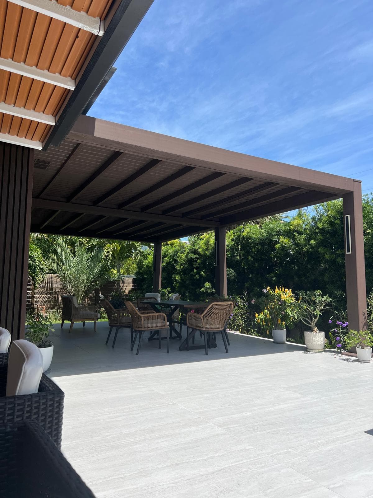 Brown WPC covered pergola over a patio dining area