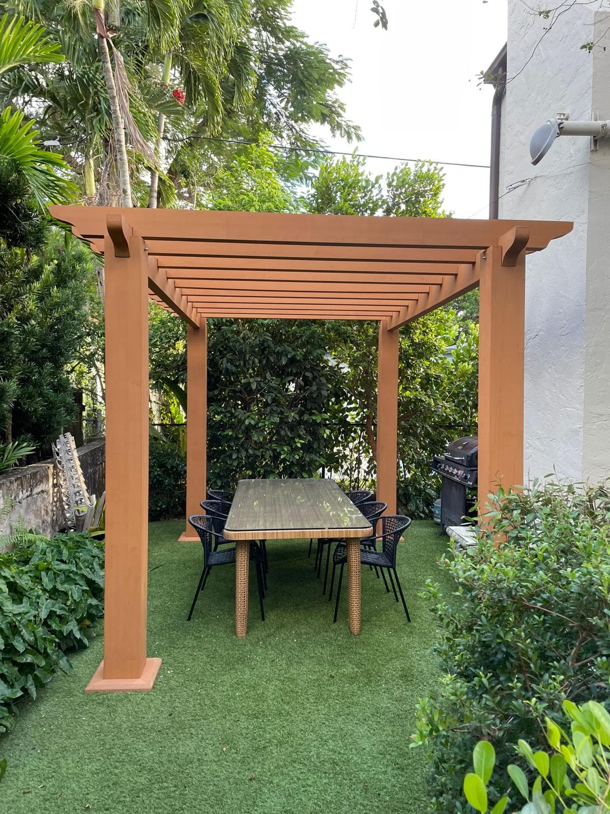 Wood-look WPC pergola over a garden dining table on turf